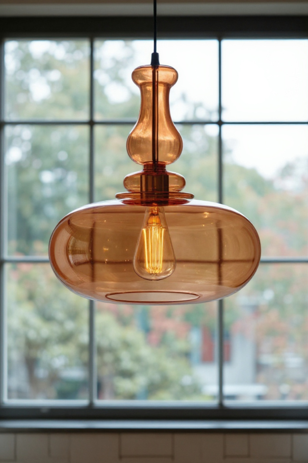 Amber glass pendant light with a blurred window background
